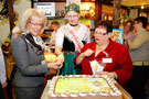 Anschnitt der Torte mit „Fit für Familie“-Logo: Landrätin Kornelia Wehlan, Flämingkönigin Eva von Holly, Bürgermeisterin Monika Nestler (von links)